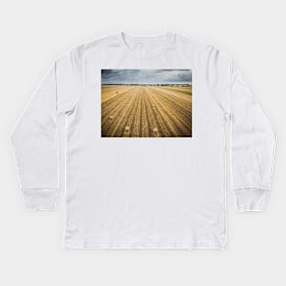 Aerial view of round hay bales on stubble with a village in the background Kids Long Sleeve T-Shirt